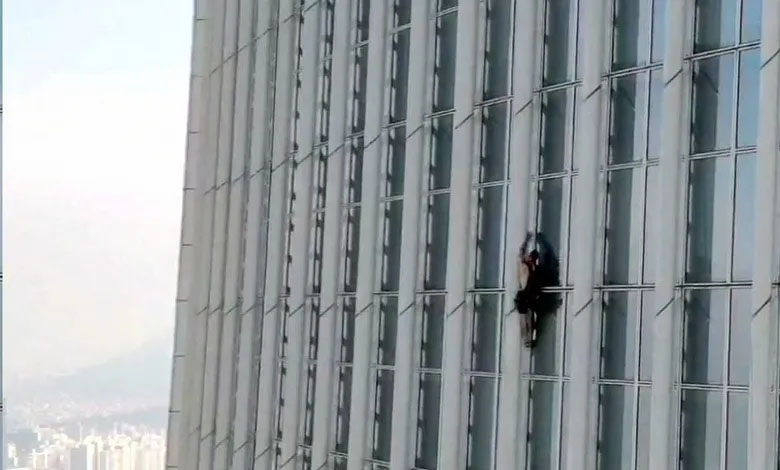 A climber risks his life to climb a giant tower without ropes